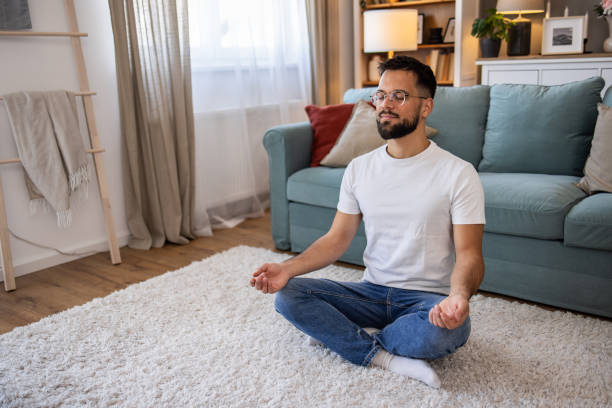 istock Young man meditating at home 2198987531