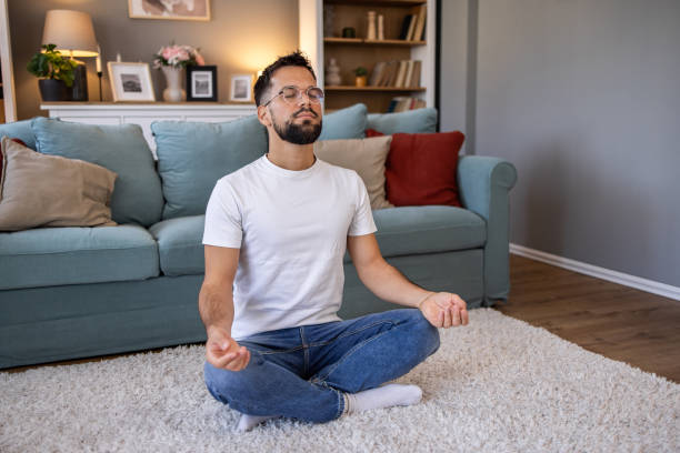 istock Young man meditating at home 2198987540