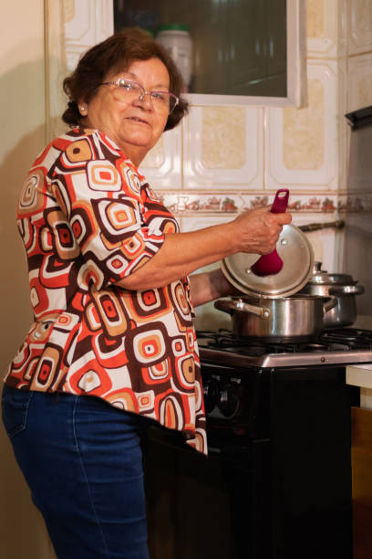 istock older woman smiles at the camera while cooking 2198989854