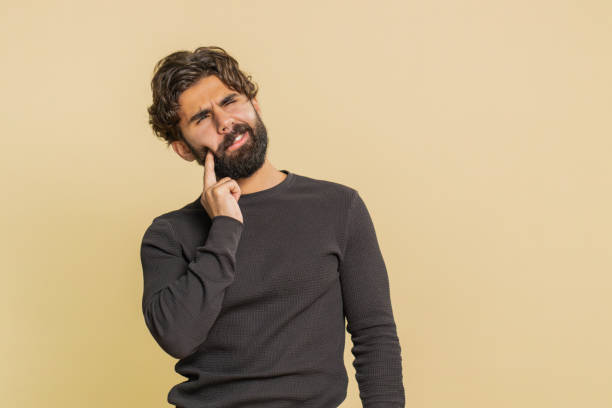 istock Young Indian bearded man touching sore cheek suffering from toothache cavities on beige background 2198990221