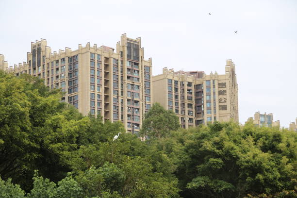 A large brown building with a green hill in the background. The building is surrounded by trees and has a bird perched on it