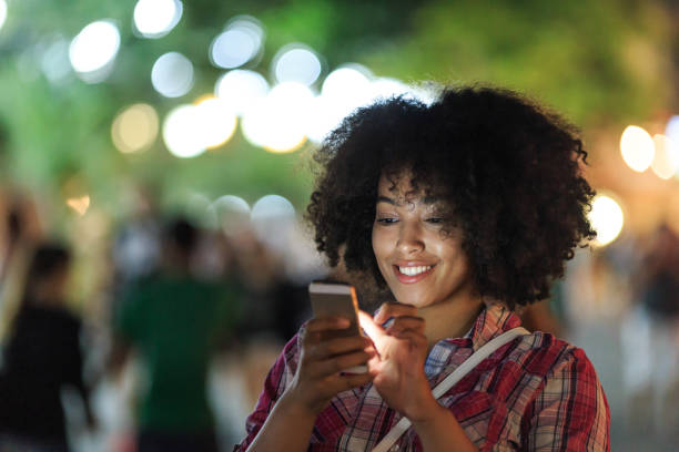 istock Woman browsing phone with city lights 2199005497