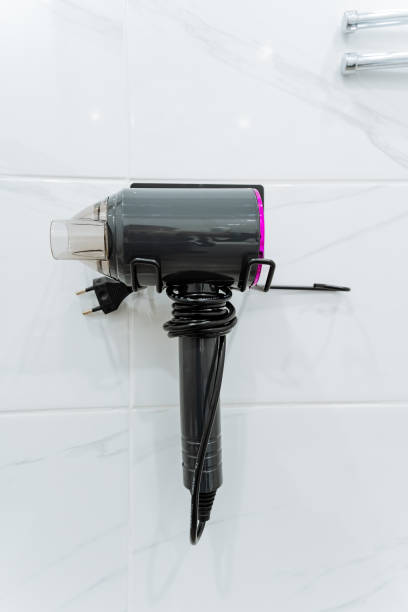 istock A hair dryer is currently hanging on a clean, white tiled wall, adding a touch of practicality to the space it occupies and serving its purpose effectively for hair styling needs 2199005801