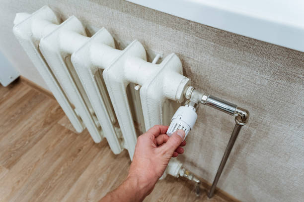 istock Adjusting a modern thermostat that is connected to a white radiator is crucial for achieving optimal home heating efficiency and overall comfort in your living environment 2199005854