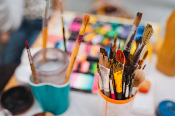 An assortment of paint brushes arranged on a table showcases a variety of colors and sizes, ready for artistic endeavors, highlighting their importance in enhancing creativity in the art world
