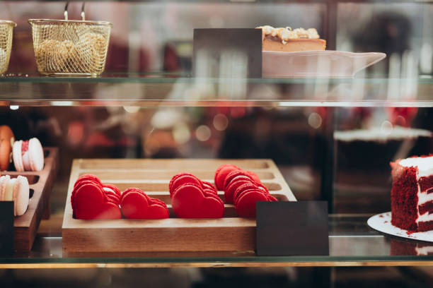 Red heart-shaped macaroons in the pastry shop window. Concept for Valentine's Day. French macarons heart shaped Valentine gift. Romantic date coffee dessert cookie confection.