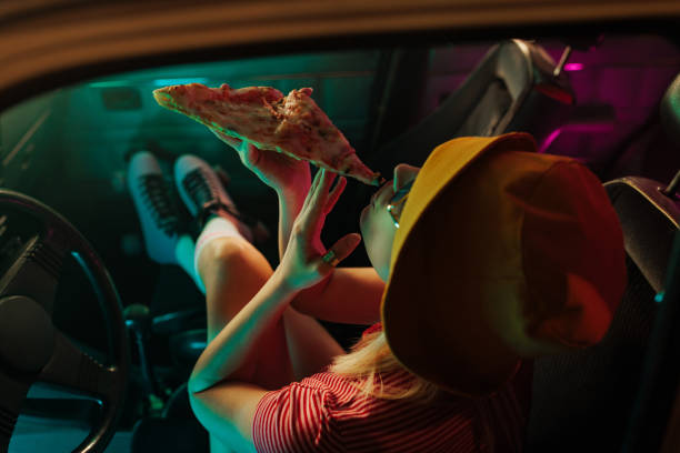 istock Girl eating pizza in car. 2199008558