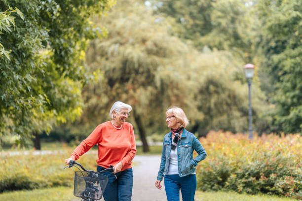 istock Senior Friends Walking in Park with Bicycle 2199008683