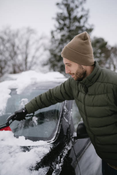 istock Man cleaning ice off his car windshield after a winter snow storm 2199014534