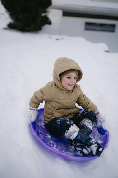 istock Child in winter sledding down a snowy hill 2199014536