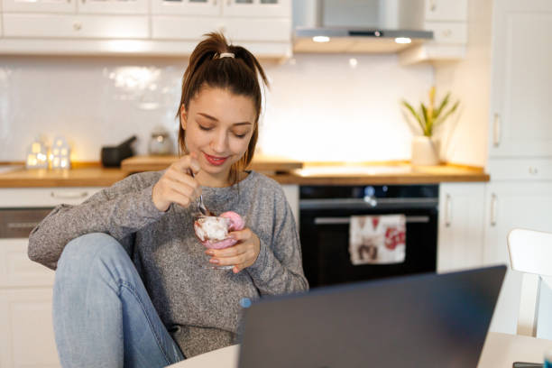 istock Woman eating ice cream while taking break from learning at home 2199016374