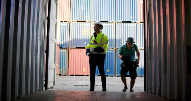 Blue collar worker works at commercial dock. Male Port Worker Opening Shipping Cargo Container to inspect the readiness of the box container