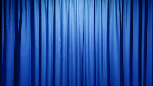 istock A luxurious, textured blue fabric curtain, draped in soft folds and illuminated with a subtle glow, creates an elegant and versatile background suitable. 2199025551