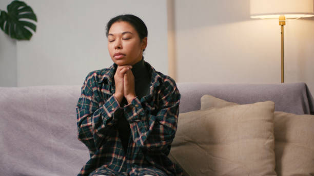 istock Hispanic woman bites lips holding hands in pray gesture 2199030775