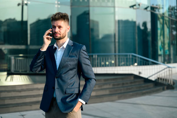 istock Bearded businessman talking on mobile phone outside office building 2199032061