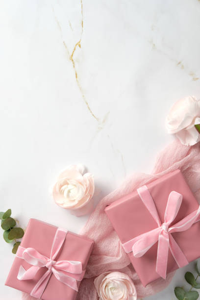 istock Pink gift boxes with rose ranunculus flowers and eucalyptus on marble background. Romantic flat lay composition. Happy Mothers Day, International womens day, birthday concept. 2199032225