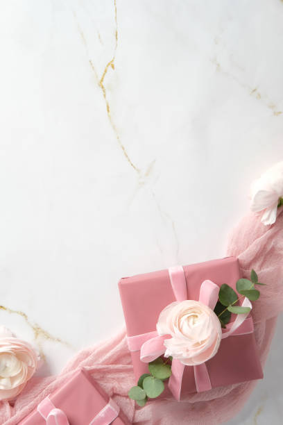 istock Pink gift boxes with rose ranunculus flowers and eucalyptus on marble background. Romantic flat lay composition. Happy Mothers Day, International womens day, birthday concept. 2199032305