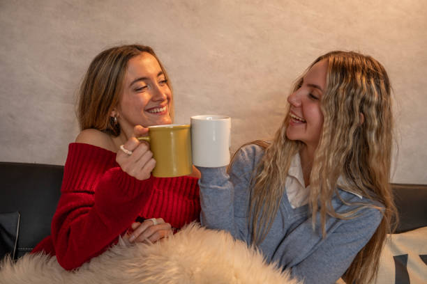 istock Two smiling women are toasting with teacups on sofa at home 2199038545