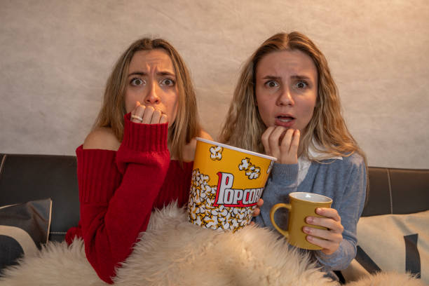 istock Two young women feeling scared while watching a movie at home 2199038561