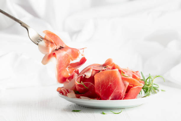 istock Prosciutto with rosemary on a white wooden table. 2199038691