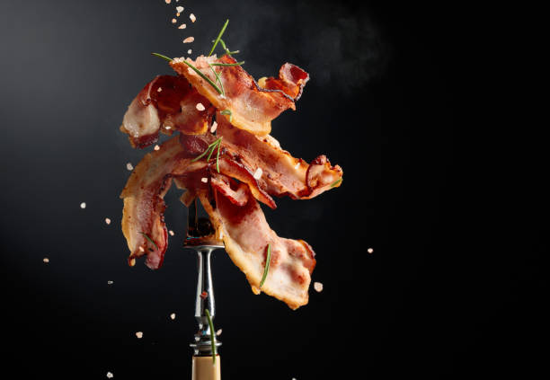 istock Fried bacon on a fork, sprinkled with rosemary and pink salt. 2199038702
