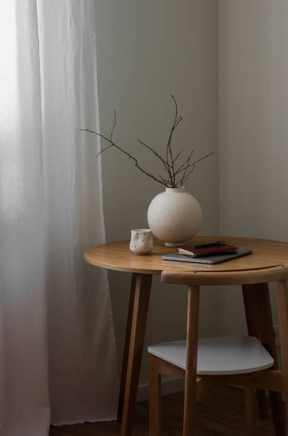 istock A round ceramic vase with branches, a laptop, a notebook, a coffee mug on a round wooden table in the living room 2199039825