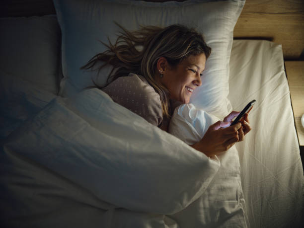 istock Above view of happy woman using mobile phone in bed. 2199041640
