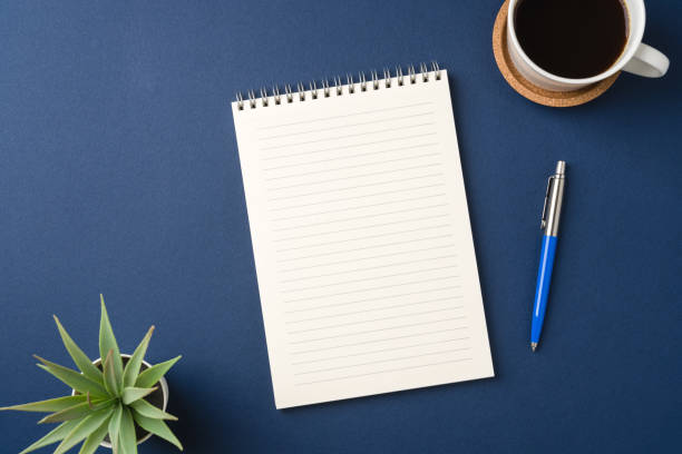 istock Top view of a workspace with a blank notebook, pen, coffee, and plant 2199042607