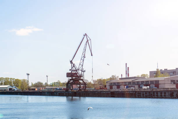 Port crane against the blue sky. Cargo transportation along the river.