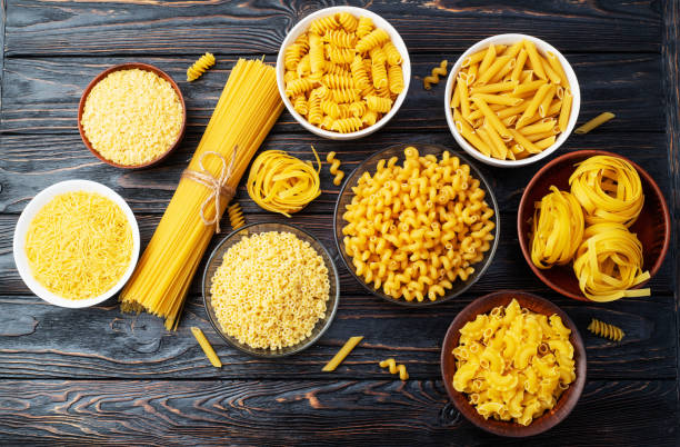 istock Assorted Uncooked Pasta in Bowls on Wooden Table 2199047100