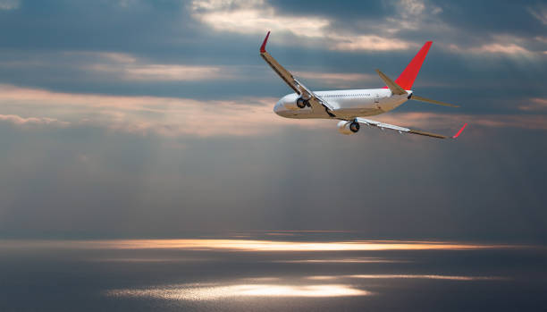 istock Airplane flying over tropical sea at sunset 2199052218