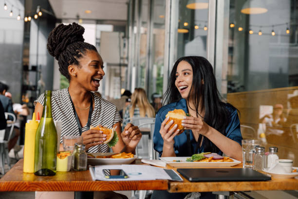 istock Two businesswomen eating hamburger at lunch break 2199053767