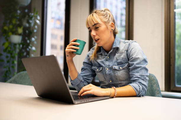 istock Young Woman Working at a Laptop and Holding a Coffee Cup 2199053795