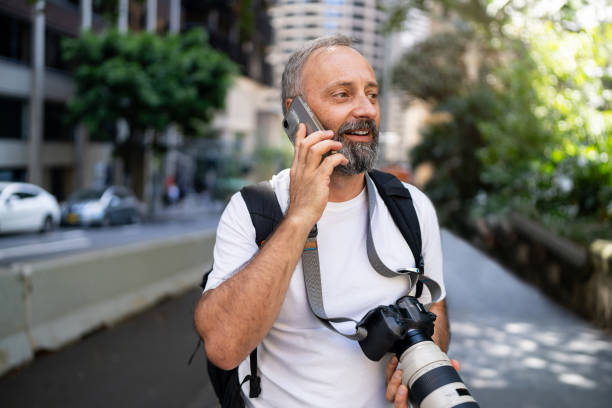 istock Man with Camera Talking on Phone Outdoors in Urban Street Setting 2199055574