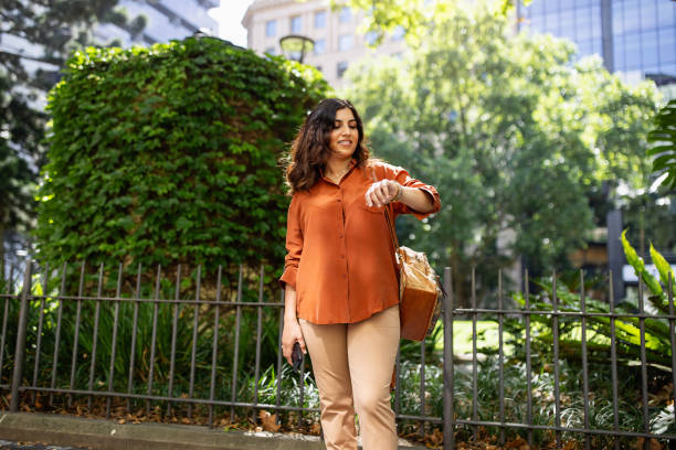Woman Walking Outdoors Checking the Time on a Sunny Day