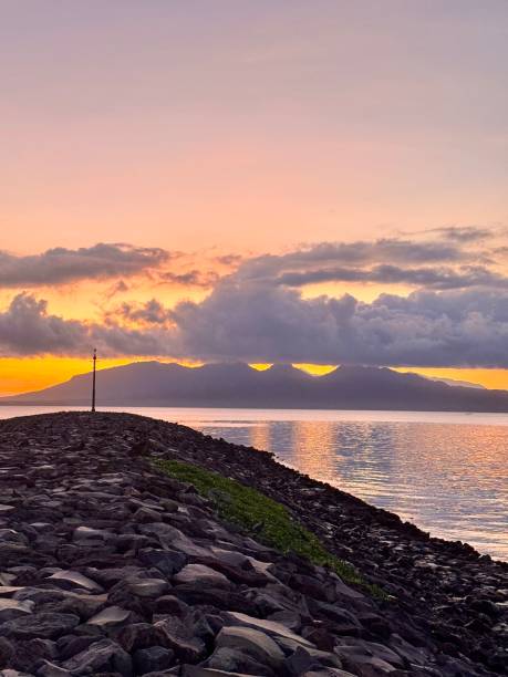 istock Scenic Sunset Over Rocky Coastal Path with Mountain Silhouette, Vibrant Sky, Cloudscape Reflection on Water, Tranquil Ocean Horizon, Serene Travel Destination, Nature Landscape, Twilight Beauty 2199056577