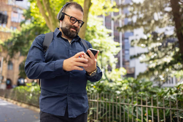 istock Man Using Smartphone Outdoors While Listening to Music Through Headphones 2199056694