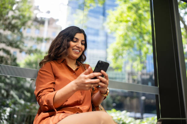 istock Smiling Woman Using Smartphone in a Bright Urban Environment 2199057516