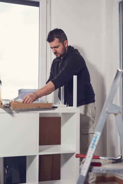 istock Man working and assembling furniture in a new apartment. 2199059837