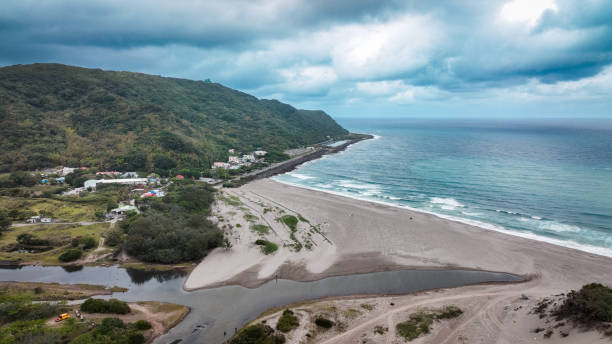 Stunning view of a serene beach in Taiwan with gentle waves lapping against the shore under a cloudy sky.