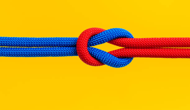 istock Red and blue ropes with reef knot isolated on yellow background 2199062376