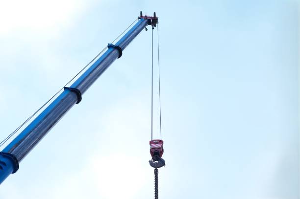 istock Blue crane arm, boom with hanging hook against clear sky. Construction and lifting heavy building materials, large components, and machinery 2199067306