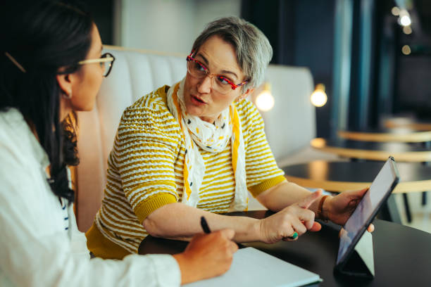 istock Mature woman giving a private teaching lesson to a young student using a tablet 2199070228