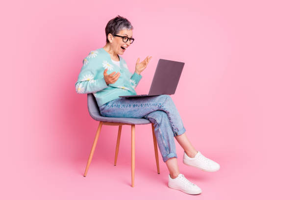 istock Charming mature woman using a laptop in a colorful setting with a cheerful expression 2199072039