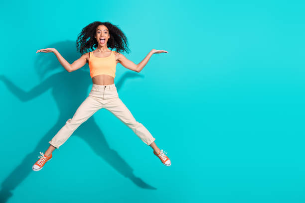 istock Energetic young woman jumping against a bright teal backdrop, exuding joy and confidence 2199074330