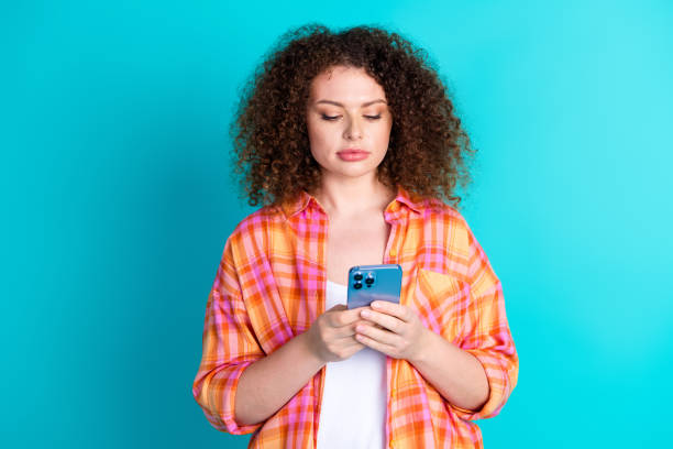 istock Young woman in a checkered shirt using a modern smartphone against a turquoise background 2199075559