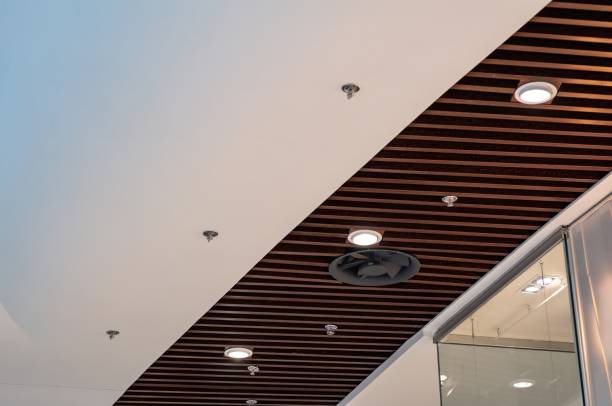 istock A sleek ceiling features alternating white panels and dark wood slats with recessed lighting and ventilation. 2199076496