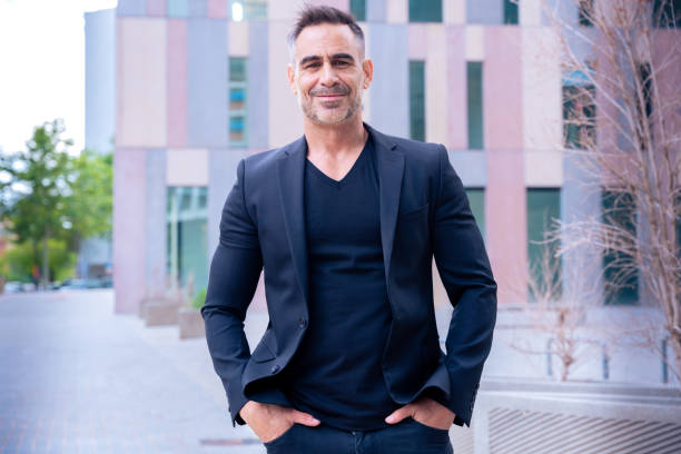 istock Smiling businessman in black suit posing confidently in urban setting. 2199078219