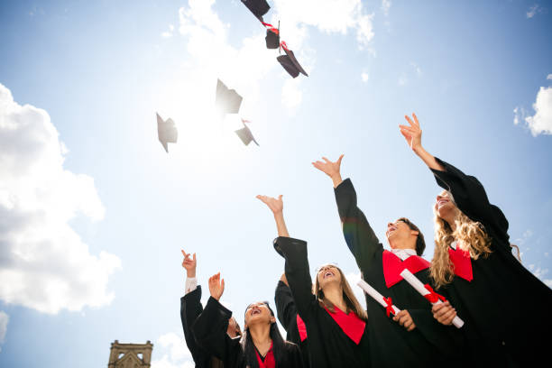 istock Graduating students celebrate by tossing caps in bright sunny sky, capturing joyful moment of achievement outdoors 2199081436