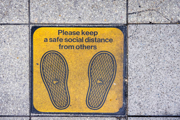 Tile on the subway platform telling the passengers to keep as much distance as possible.  The photograph is taken at the 96th Street - Lexington Avenue subway station on Manhattan, New York